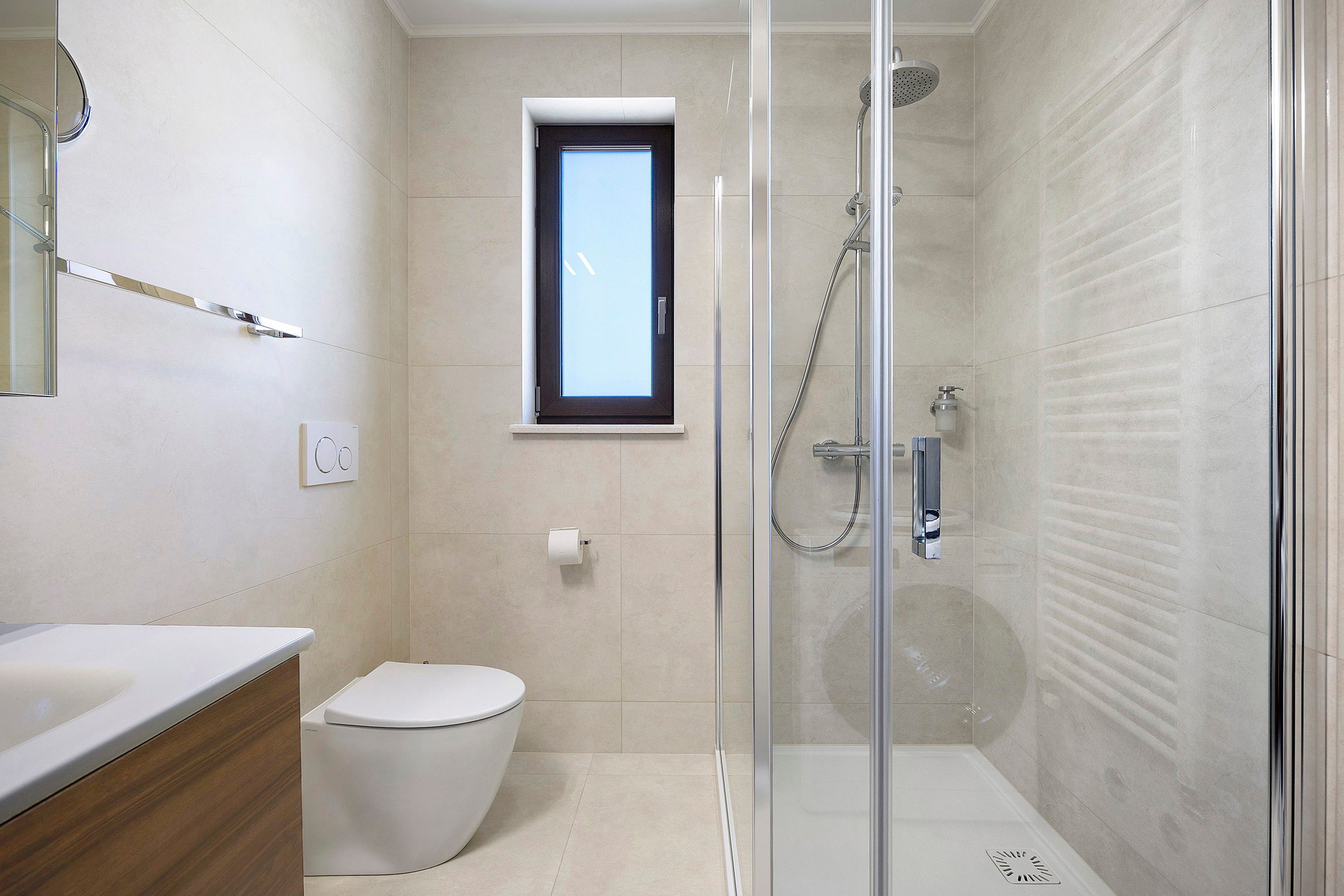 Une salle de bain moderne dotée d’une douche à parois de verre, de toilettes et d’un meuble-lavabo avec un miroir.