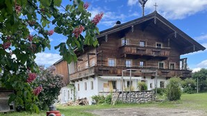 Un immeuble en bois à plusieurs étages, doté de balcons, d’un mur en pierre et d’une borne d’incendie au premier plan.