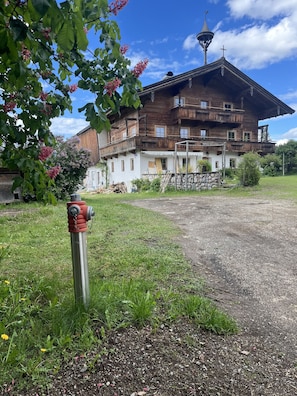 Ein mehrstöckiges Holzgebäude mit Balkonen, einer Steinmauer und einem Hydranten im Vordergrund.