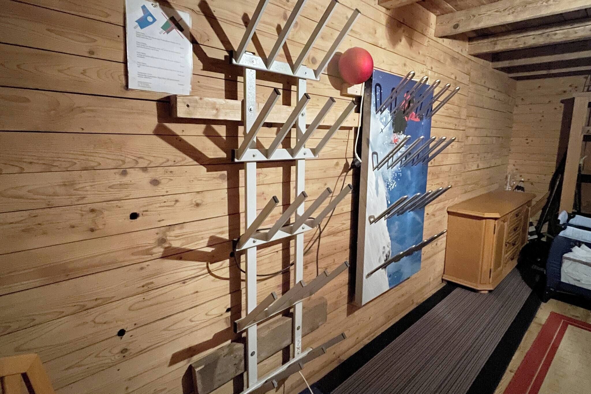 Ein Holzinnenraum mit einem Skiständer, einem Poster und einer Holzkabine.