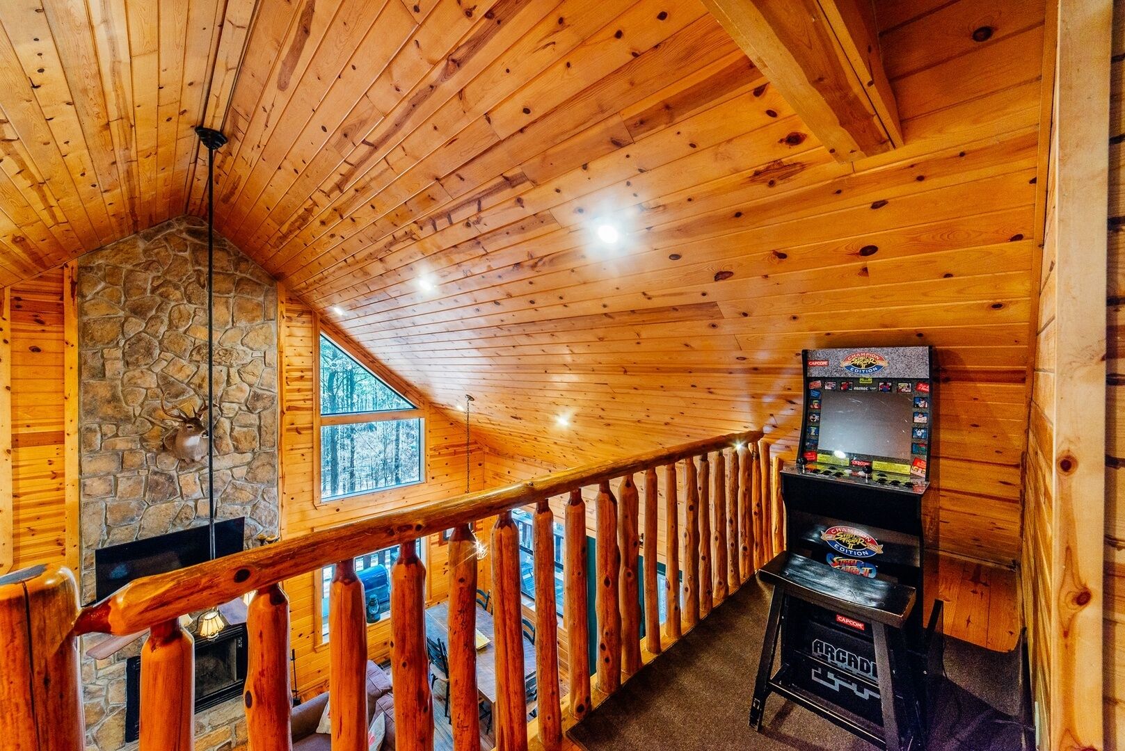 A wooden interior with a stone fireplace, a wooden staircase, and a video game console.