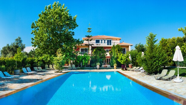 Une piscine avec des chaises longues et une maison en arrière-plan.
