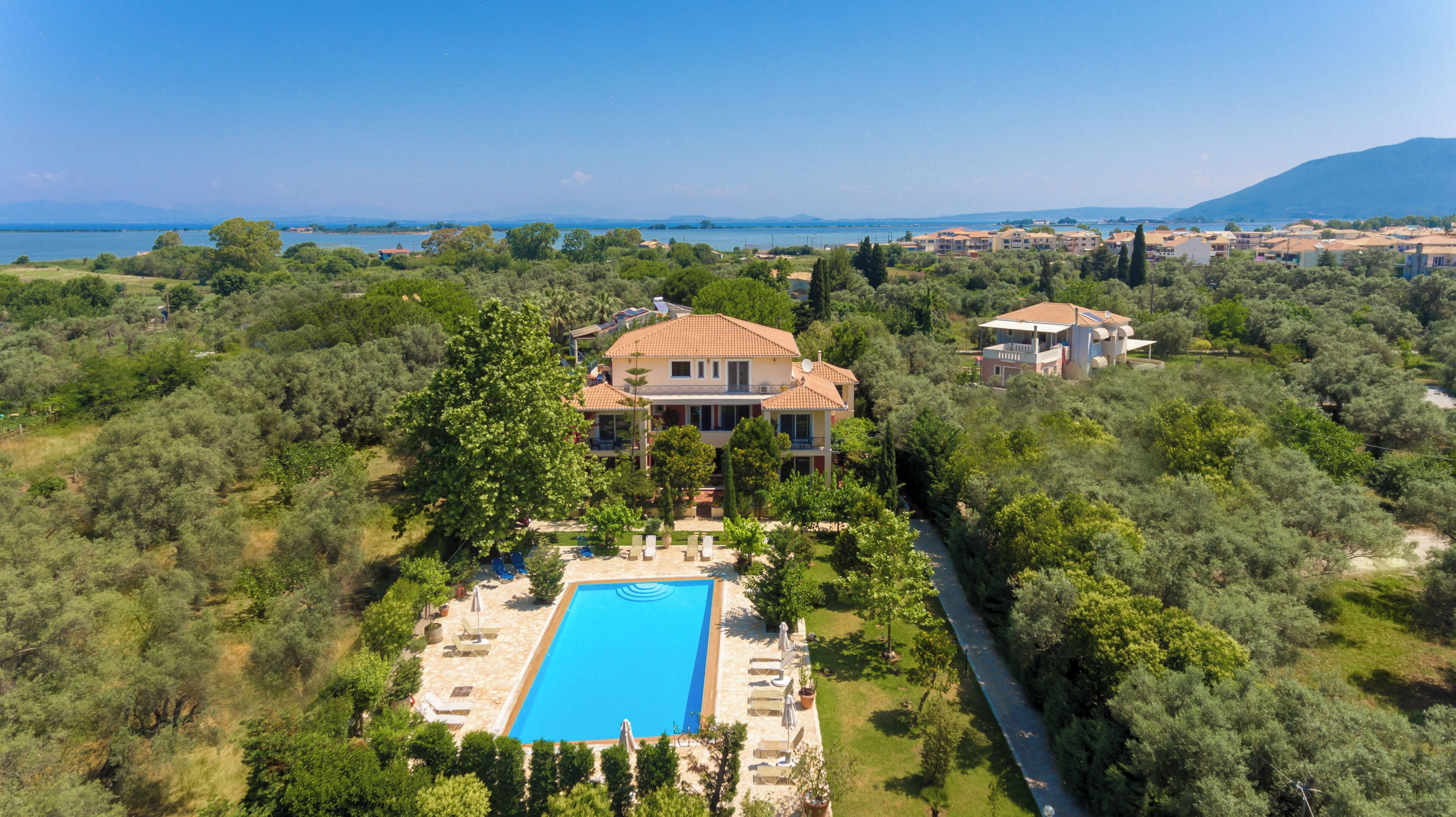 A large house with a swimming pool surrounded by lush greenery.