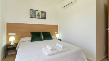 Een hotelkamer met een groot bed, twee bedlampen, een wandairconditioner en een ingelijst schilderij boven het bed.