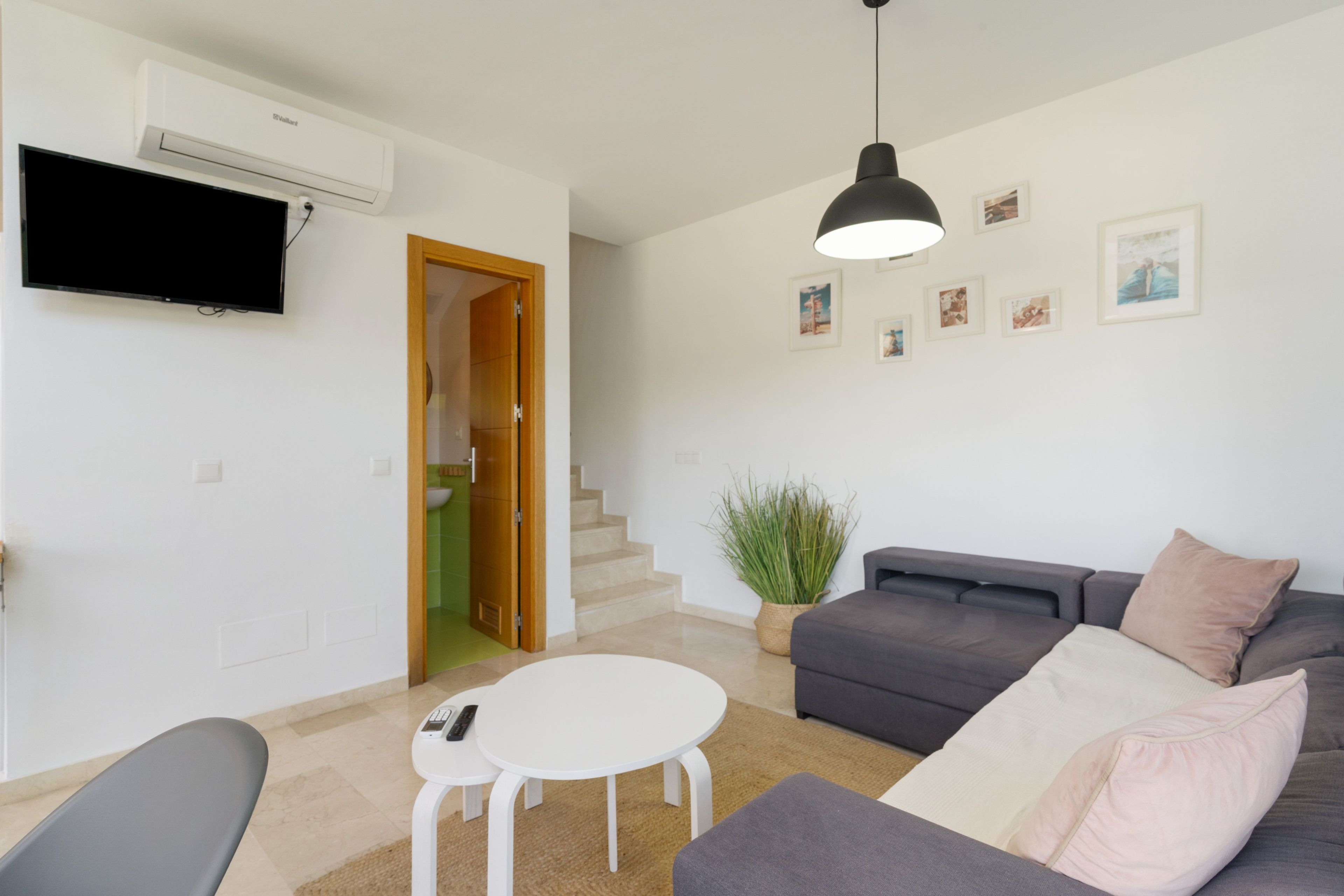 Ein modernes Wohnzimmer mit einem grauen Sofa, einem weißen Couchtisch und einer schwarzen Pendelleuchte.