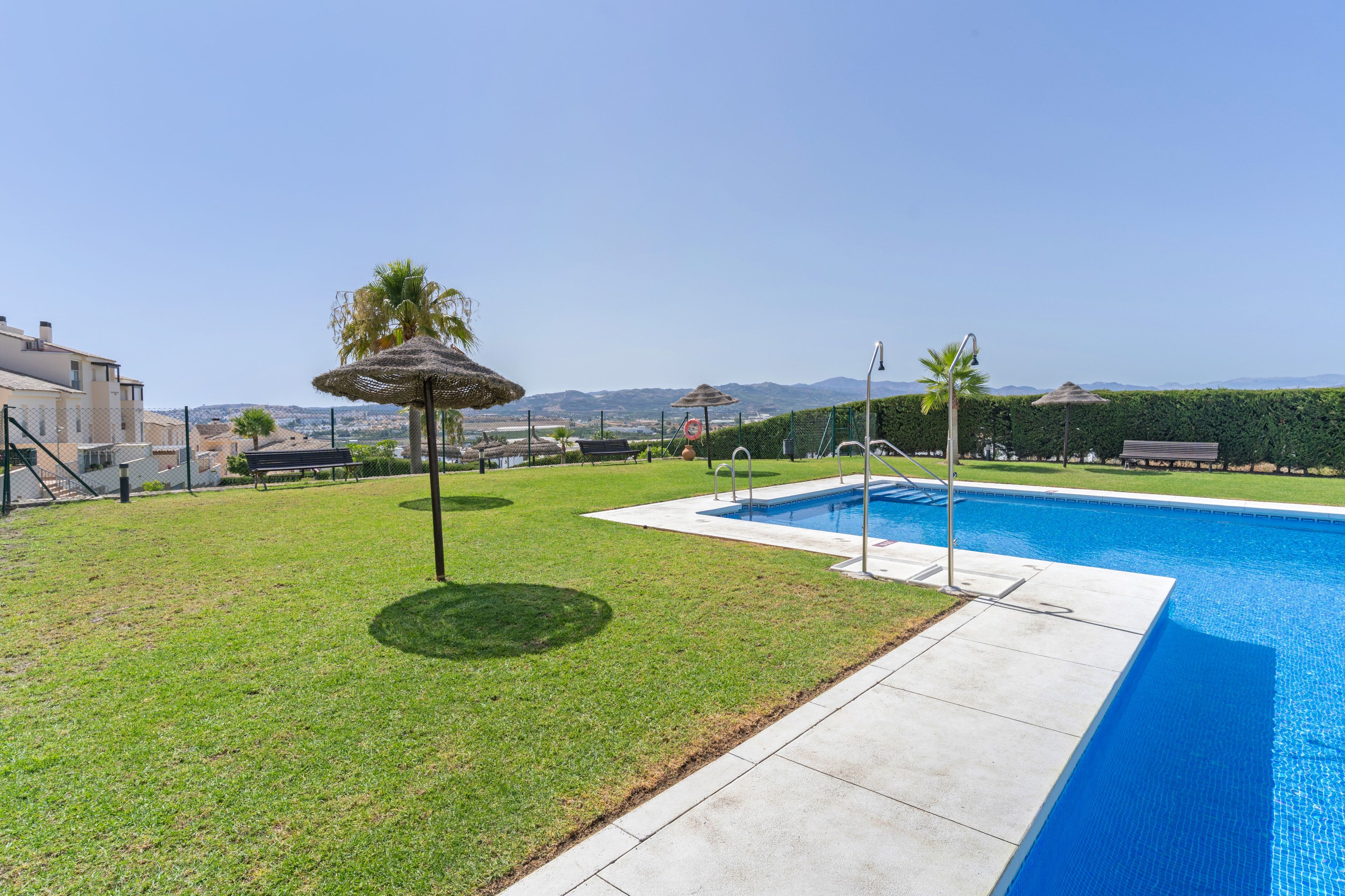 Una piscina con vistas despejadas del paisaje circundante, que incluye una zona de césped y algunos árboles.