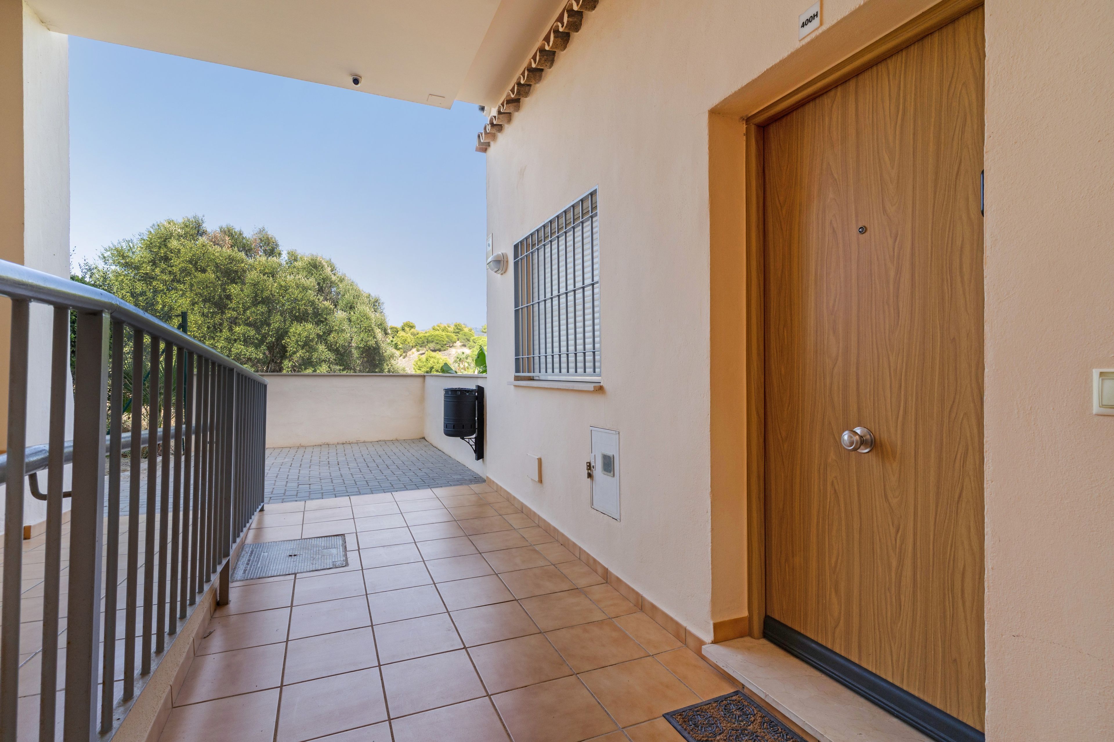 Ein Balkon mit Fliesenboden, Metallgeländer, einer Tür und einem Fenster mit Gitterstäben.