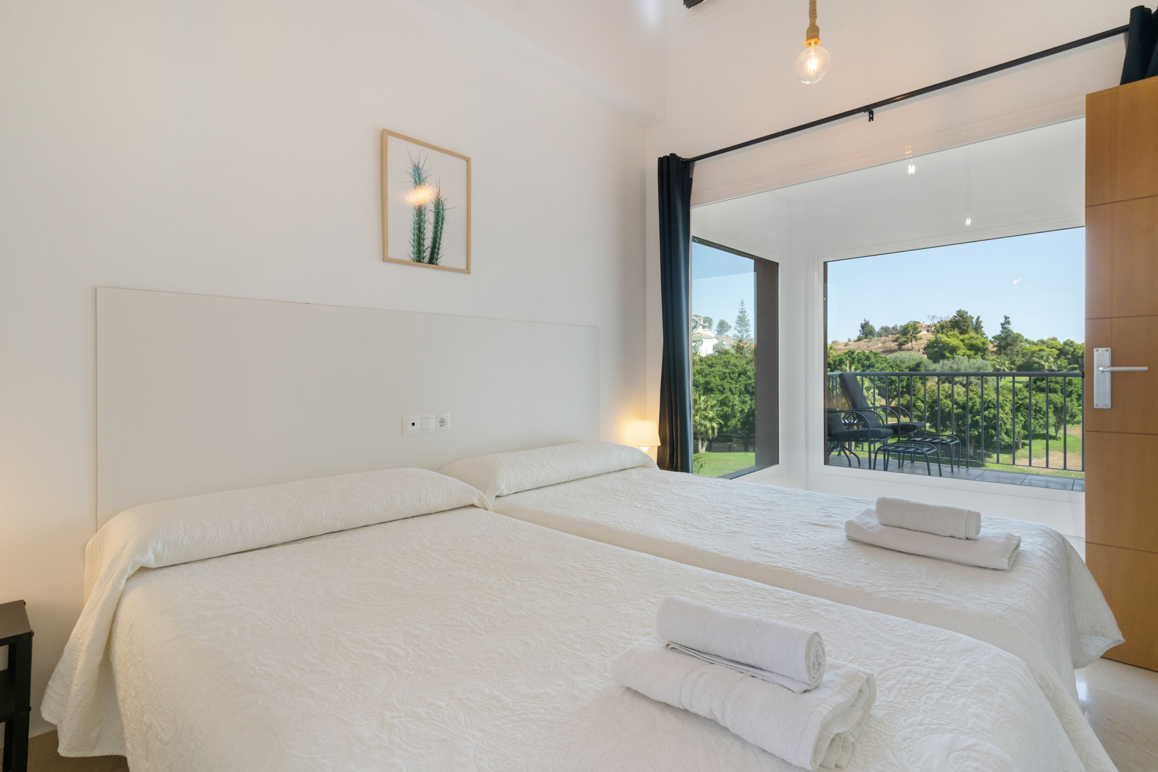 Une chambre d’hôtel avec deux lits, une grande fenêtre et une vue sur un paysage verdoyant.