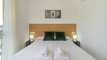 Ein Hotelzimmer mit einem großen Bett, zwei grünen Kissen, zwei Nachttischlampen und einem Gemälde an der Wand.
