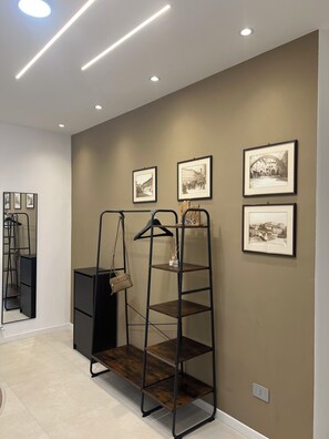 Ein Zimmer mit einem schwarzen Metallregal, einem Spiegel und gerahmten Schwarz-Weiß-Fotos an der Wand.