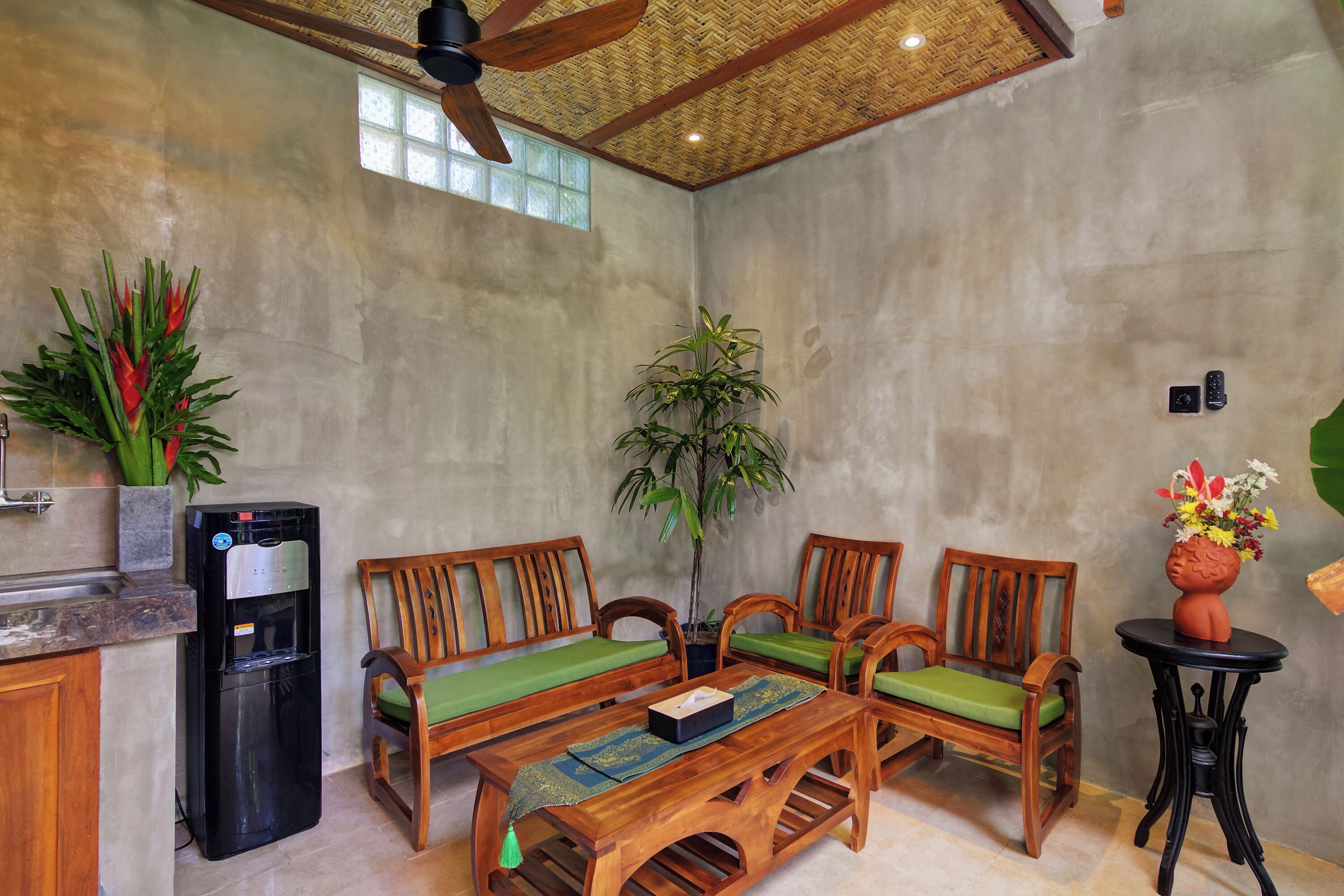 A room with a ceiling fan, a water dispenser, wooden furniture, and a potted plant.