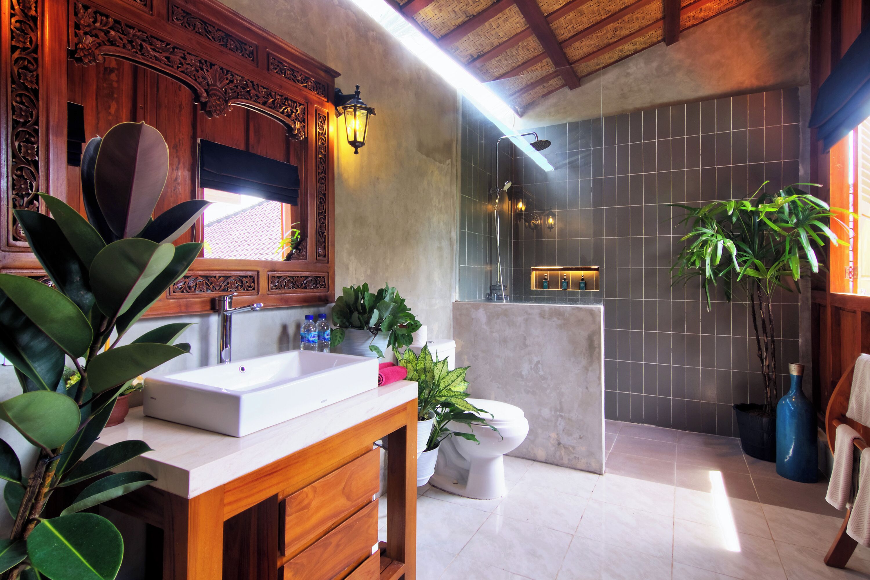 A bathroom with a wooden vanity, a white sink, a toilet, and a shower area.