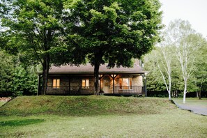A two-story house with a porch, brick exterior, and a large tree in front. - Le Doux Boisé - Beach Access - 15 min. from Mont Tremblant   (LA CONCEPTION)