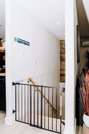 A modern interior with a staircase, a sign indicating a direction, and a potted plant. - Le Doux Boisé - Beach Access - 15 min. from Mont Tremblant (LA CONCEPTION)