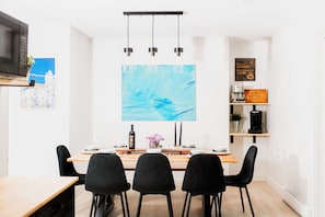 Un comedor moderno con una mesa de madera, sillas negras y un cuadro abstracto grande en la pared.