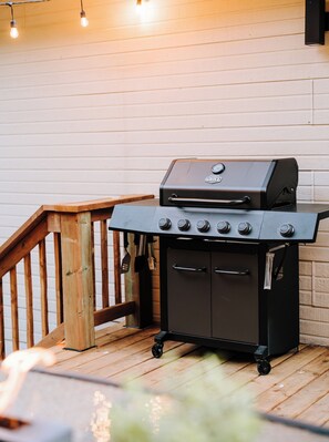 Un barbecue doté d’un thermomètre numérique, d’un meuble latéral et d’une terrasse en bois.