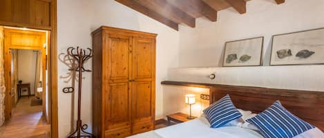 A bedroom with a bed, wooden wardrobe, and a coat rack.