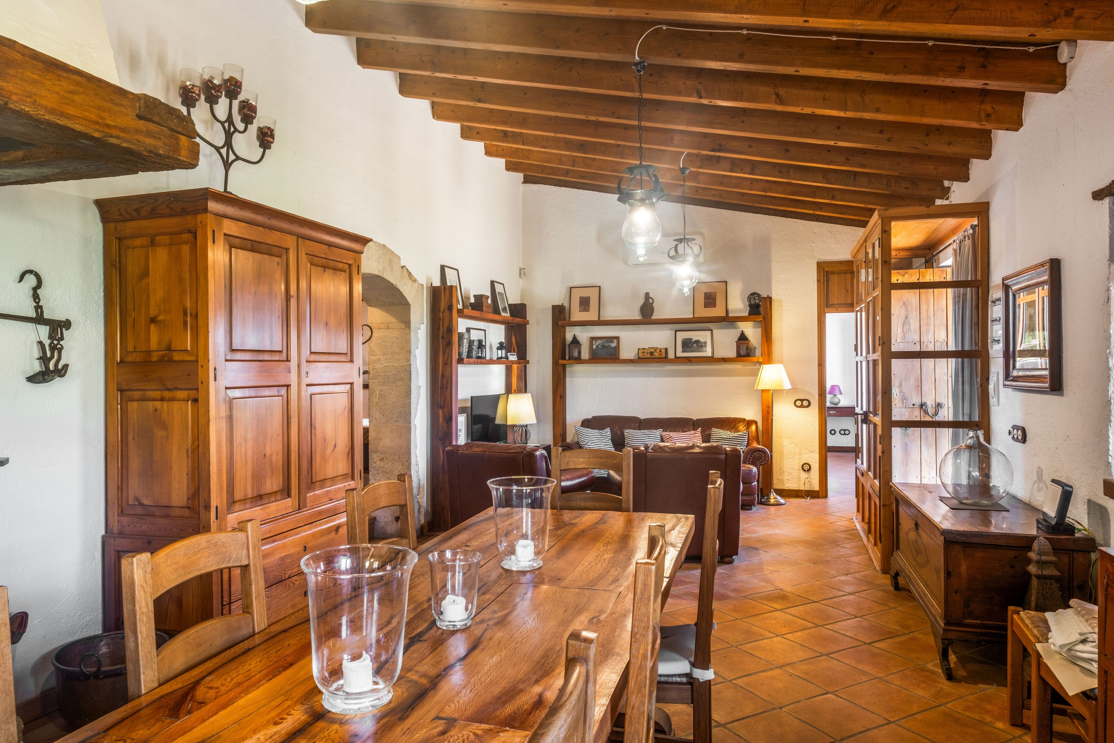 Uma área de jantar rústica, com móveis de madeira, piso de azulejos e parede de pedra.