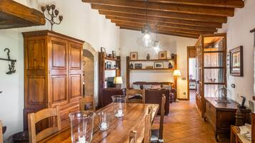 Uma área de jantar rústica, com móveis de madeira, piso de azulejos e parede de pedra.