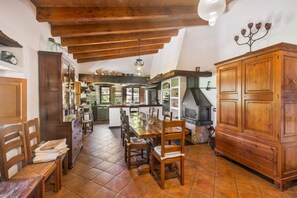A rustic kitchen with wooden beams, a central island, and a large stove.