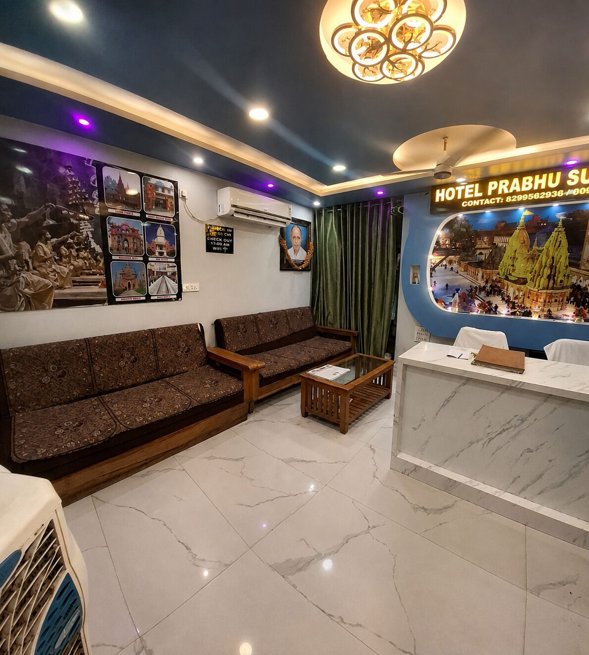 A hotel lobby with a reception desk, a sofa, a coffee table, and a wall with travel posters.