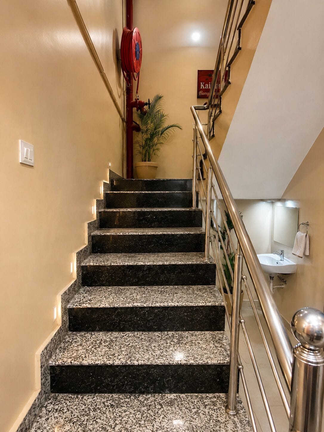 A staircase with a handrail, a potted plant, and a sign on the wall.