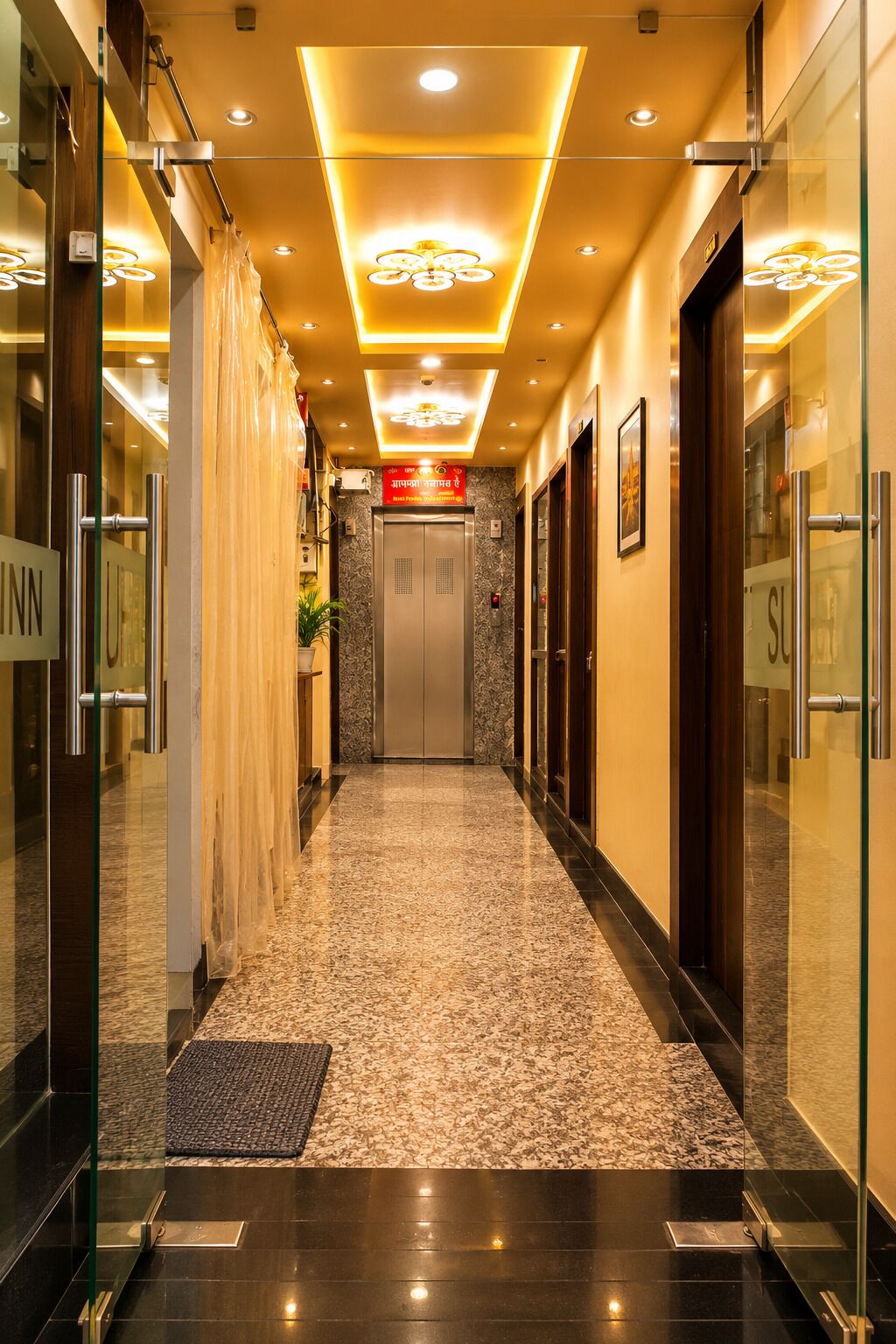 Ein Hotelgang mit Marmorboden, Glastüren und einer Rezeption.
