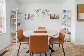 Una habitación con una mesa redonda, dos sillas y una estantería con libros y objetos decorativos.