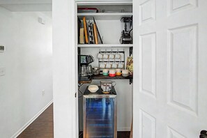 Una cocina con cafetera, microondas y tostadora. Hay un perchero con tazas y un cartel que dice 'Solo dame café y nada más'.