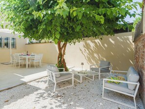 An outdoor seating area with a table, chairs, and a tree providing shade. - Beautiful  villa for 5 people with WIFI, A/C, TV and patio (Viareggio)