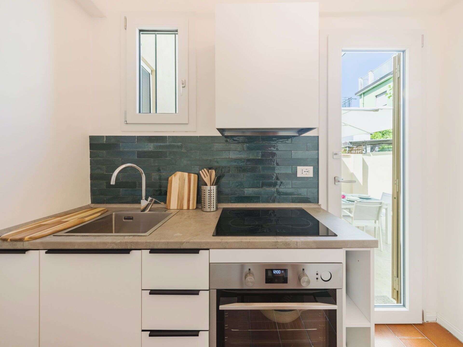 A modern kitchen with a built-in oven, a sink, and a window above the countertop.