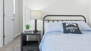 A bedroom with a bed, a bedside table with a lamp, and a wall-mounted light fixture. - Roadmap Lodging: Modern Waterview, 4BR Lakefront Monthly, Pet OK (Columbus)