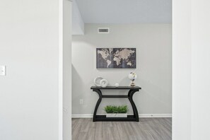 A room with a world map on the wall, a black console table with decorative items, and a plant in a white planter. - Roadmap Lodging: 4BR on the Water, Patio & Grill (Columbus)