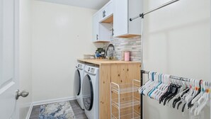 A laundry room with a washing machine, a drying rack, and a cabinet above the machine. - Roadmap Lodging: Modern Waterview, 4BR Lakefront Monthly, Pet OK (Columbus)