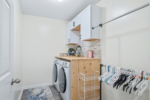 Ein Waschraum mit Waschmaschine, Wäscheständer und einem Schrank darüber.