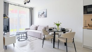 Een moderne woonkamer met een bank, een eettafel, stoelen en een keukenhoek.