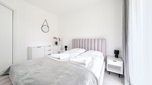 Een moderne slaapkamer met een bed, nachtkastjes, een radiator en een wandlamp.