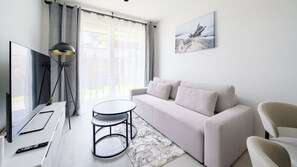 Ein modernes Wohnzimmer mit einer Couch, einem Couchtisch, einem Fernseher und einem Bild an der Wand.