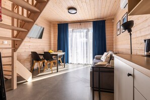A compact room with a dining area, a sofa, a kitchenette, and a staircase. - Comfortable Holiday Homes With SPA Rewal (Rewal)
