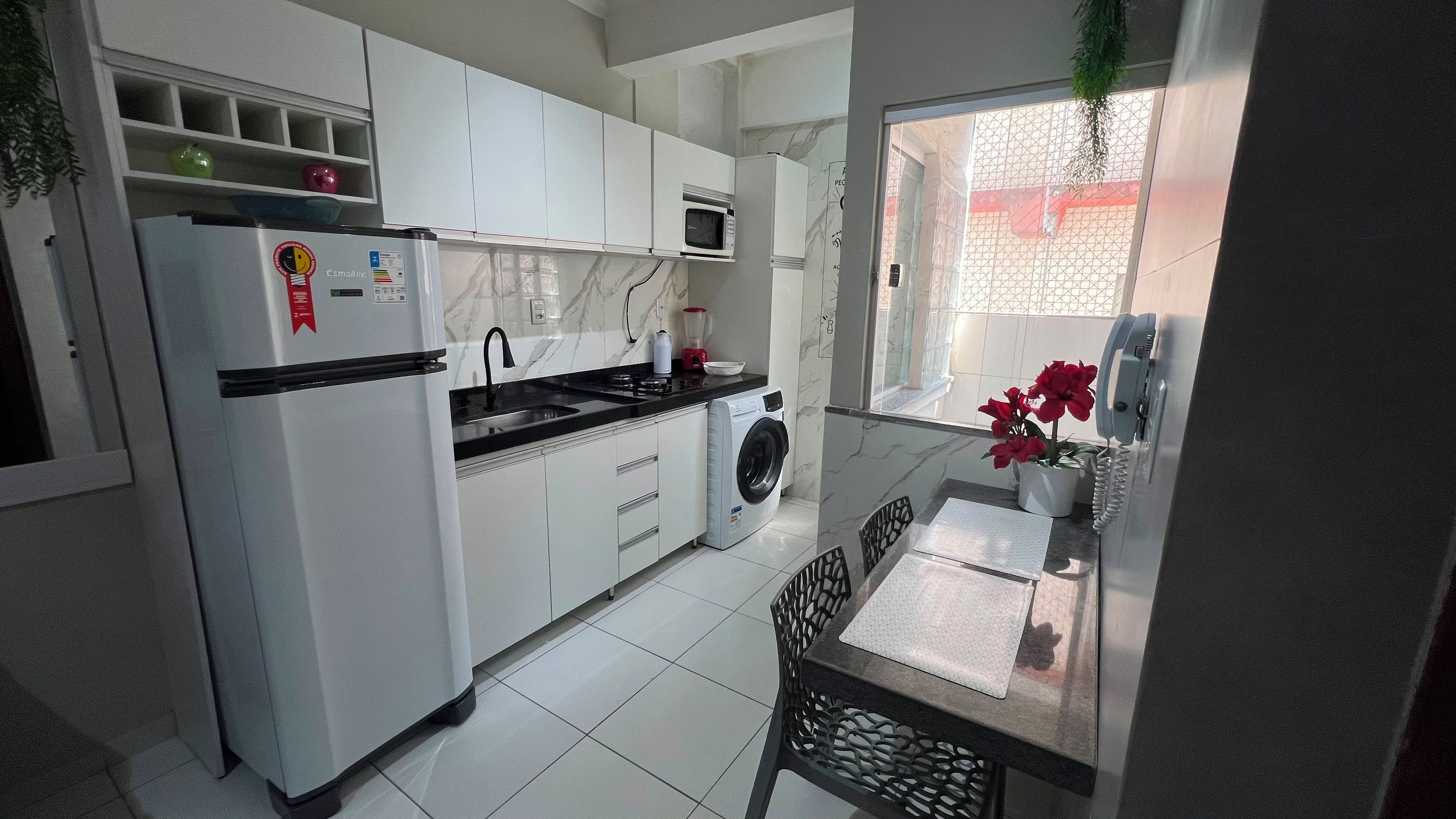 A compact kitchen with a refrigerator, microwave, sink, and a washing machine.