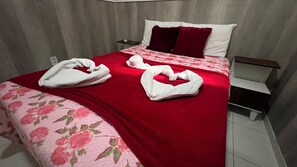 A hotel room with a bed, a red blanket, and two towels arranged on the bed. - 105 AP 2 Qtos Prático e Funcional (Belém)