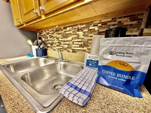 A kitchen with a granite countertop, a stainless steel sink, wooden cabinets, and a mosaic backsplash. - Oceanfront 1BR Sleeps 4-6 Myrtle Beach 421 (Myrtle Beach)
