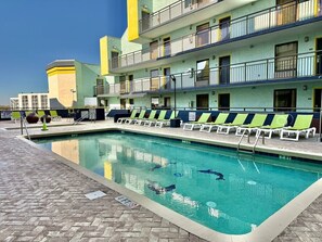 A swimming pool with lounge chairs and a building with balconies. - Oceanfront 1BR Sleeps 4-6 Myrtle Beach 421 (Myrtle Beach)