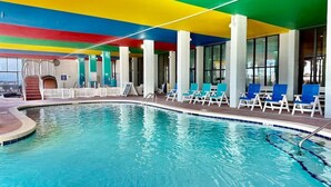 An indoor swimming pool with a colorful ceiling, lounge chairs, and a view of the outside. - Oceanfront 1BR Sleeps 4-6 Myrtle Beach 421 (Myrtle Beach)