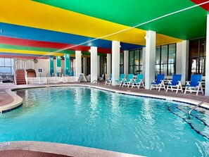An indoor swimming pool with a colorful ceiling, lounge chairs, and a view of the outside. - Oceanfront 1BR Sleeps 4-6 Myrtle Beach 421 (Myrtle Beach)