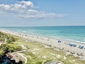 A beach with a wooden walkway leading to the water, umbrellas, and a clear sky. - Oceanfront 1BR Sleeps 4-6 Myrtle Beach 421 (Myrtle Beach)