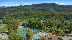 Un complexe hôtelier doté de courts de tennis, d’une piscine et offrant une vue sur un paysage montagneux.