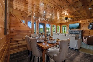 A wooden cabin interior with a dining area, sofa, and fireplace. - MTN Views|2 King Suites|Private|HotTub|Game Room|+ (Gatlinburg)