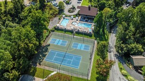 An aerial view of a property with a tennis court, a swimming pool, and a building with a sloped roof. - MTN Views|2 King Suites|Private|HotTub|Game Room|+ (Gatlinburg)