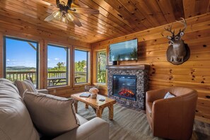 A cozy cabin interior with a stone fireplace, leather furniture, and a mounted deer head. - MTN Views|2 King Suites|Private|HotTub|Game Room|+ (Gatlinburg)